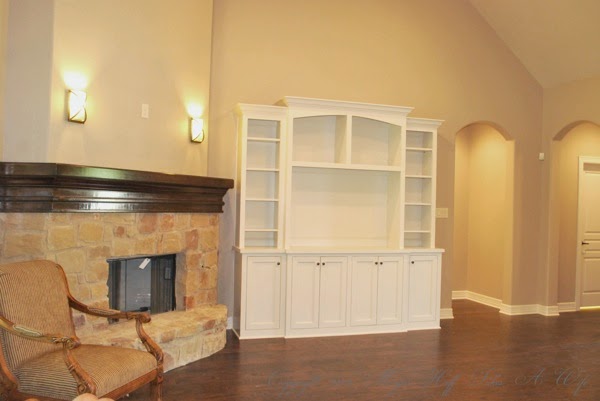 Living room with stone fireplace white built in and wood floors