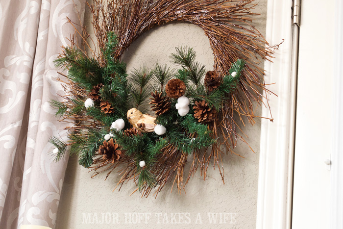 Bird on Evergreens for winter wreath. World Market inspired wreath. A fun twist on a Christmas wreath. Make a winter wreath that will last all season long and well past. This cute grapevine wreath is adorned with a tiny bird, pinecones, greenery and pom poms. You won't believe how cheap and easy this was to make! And so simple! #Christmas #winter #holiday #wreath #nature #knockoff
