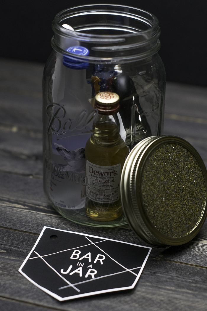 mason jar filled with booze bottles, bottle openers and other mini bar items