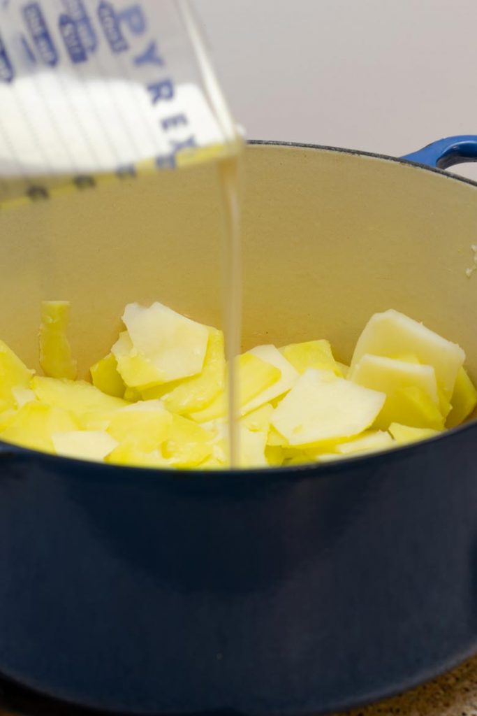 Stirring in cream and spices to a pot of boiled sliced potatoes