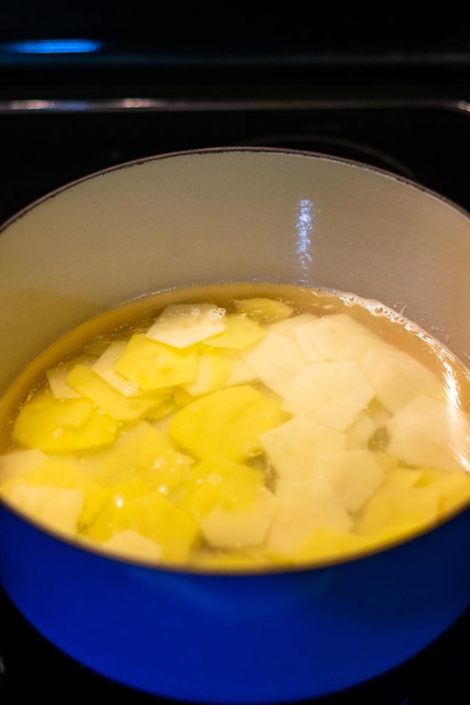 boiling potato slices on the stovetop for a savory potato pie