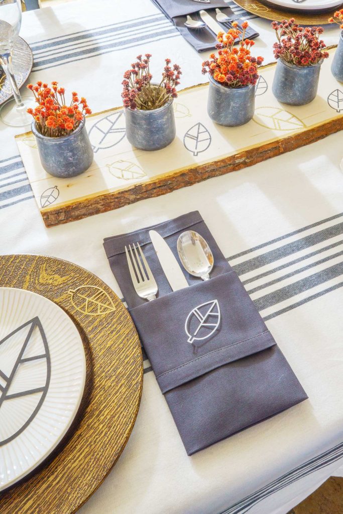 Looking for a modern rustic Thanksgiving tablescape? Use your Cricut to make these DIY chargers, a raw wood centerpiece, and wall art for the holiday!