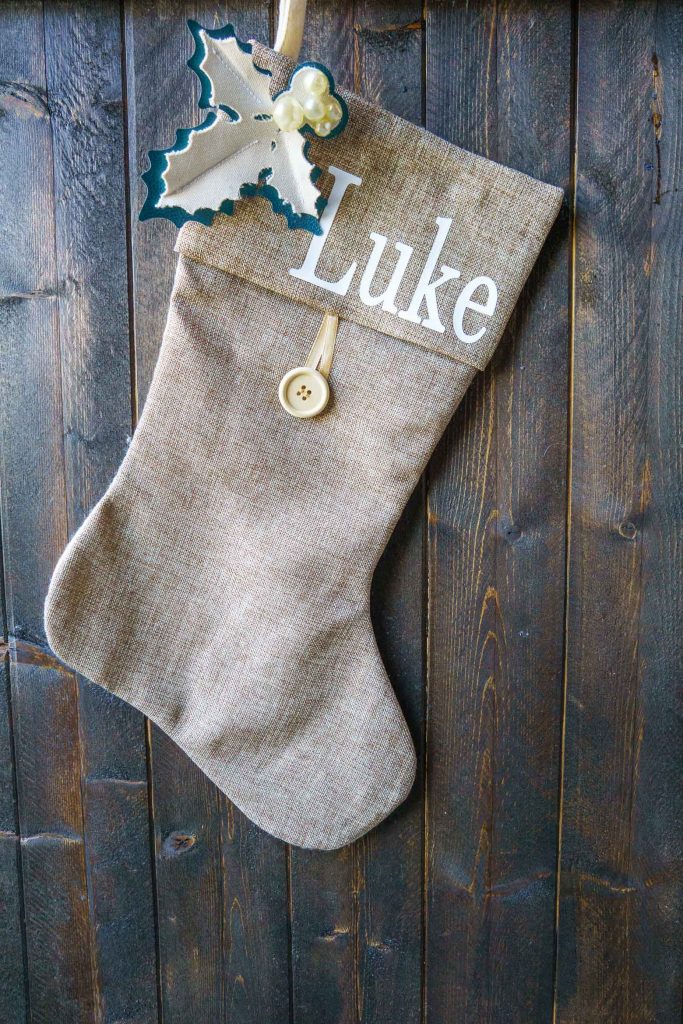 Level up a store bought stocking with homemade holly from leather and canvas on a Cricut machine. Add fonts to make it a personalized Christmas stocking!