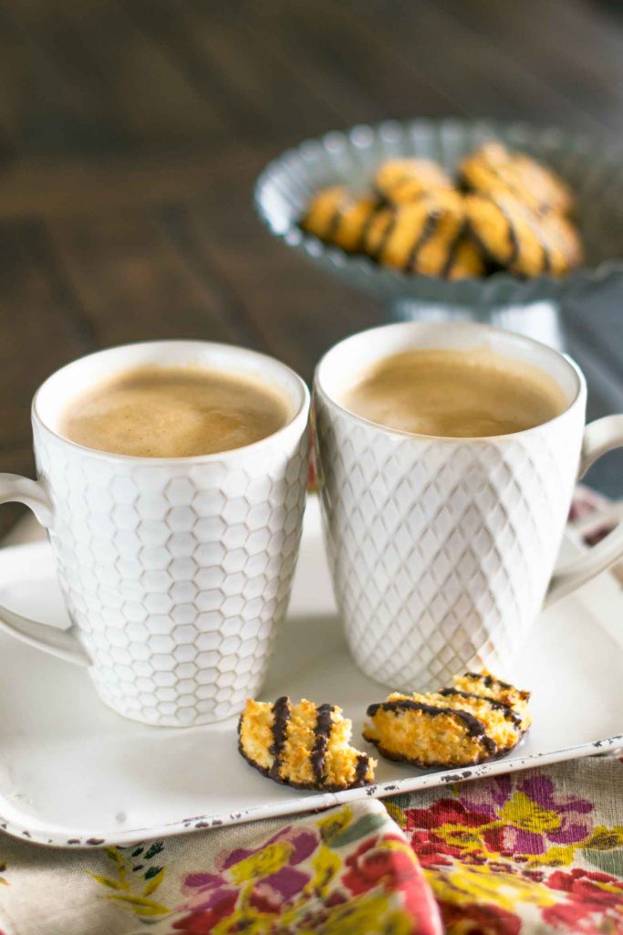 Vanilla caramel mocha lattes in white latte cups on a white tray with chocolate coconut cookies