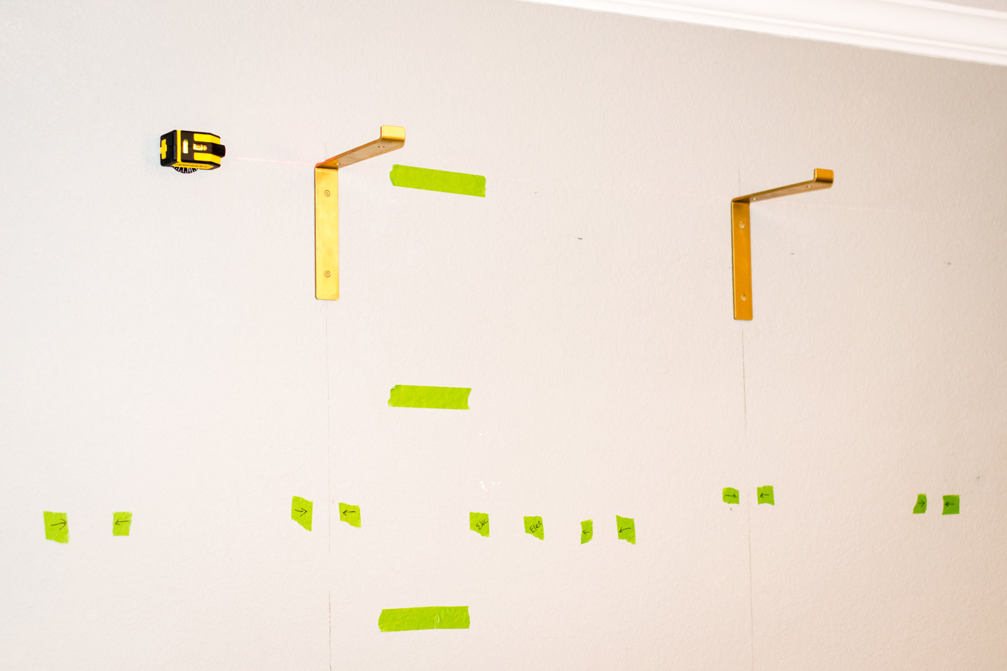 installing shelf brackets by finding studs in the wall and using a laser level