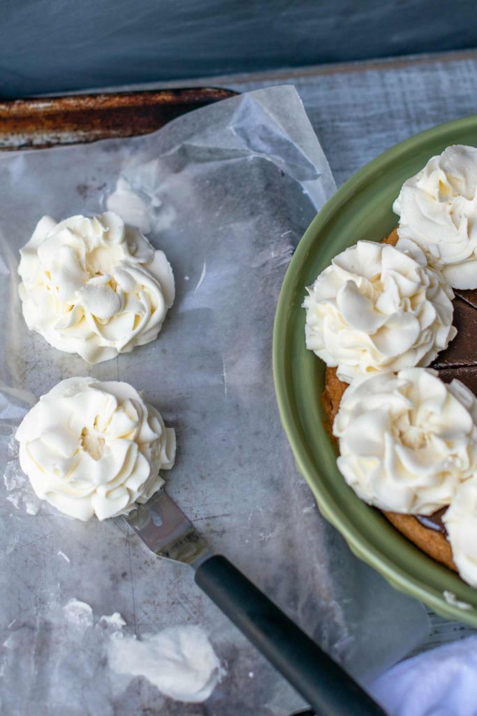 sturdy whipped cream frosting is used to pipe flower shapes to decorate a pie or cake