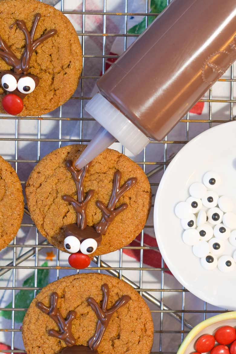 Piping chocolate antlers on to gingerbread reindeer cookies