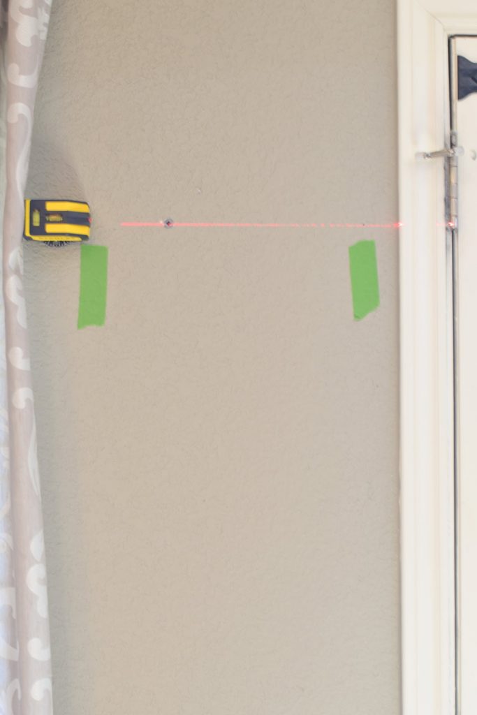 Using a laser level to hang a shelf while also finding available studs and using wall anchors where missing