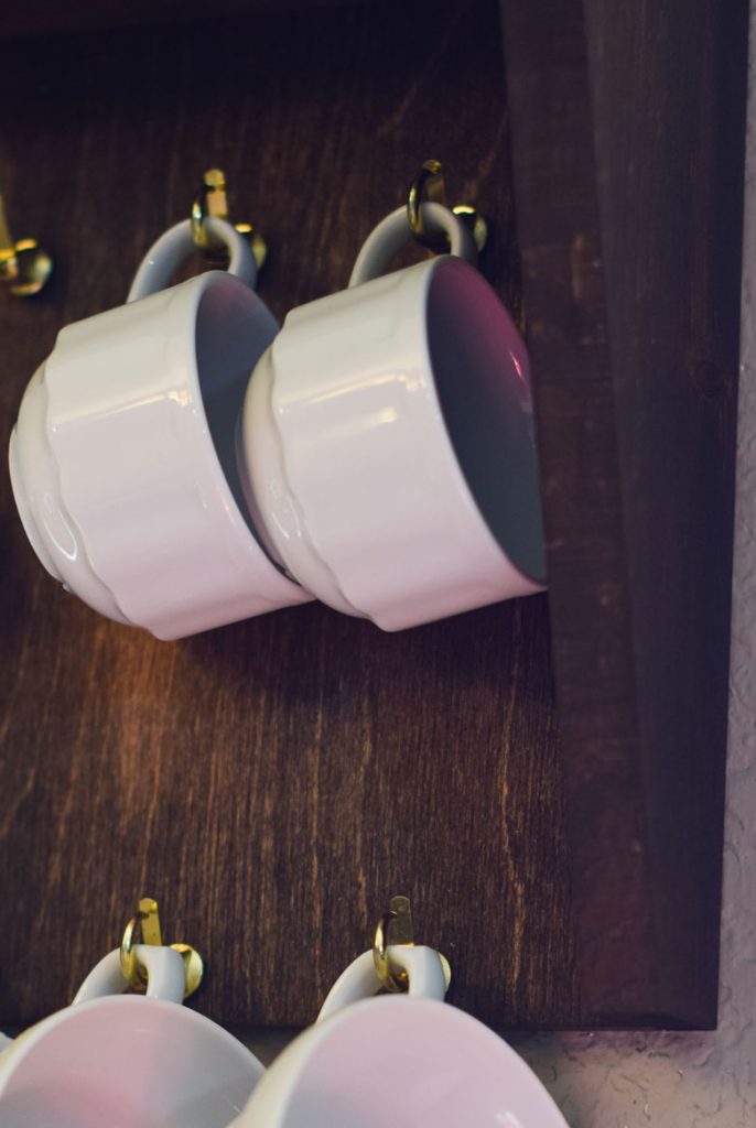 Cup hooks are screwed into this kitchen wall shelf for an easy DIY wall mug rack