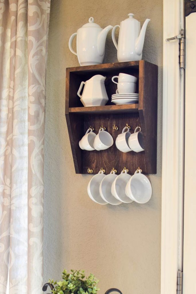 White dishes and cups hanging on a small dining room shelf for cup and mug storage