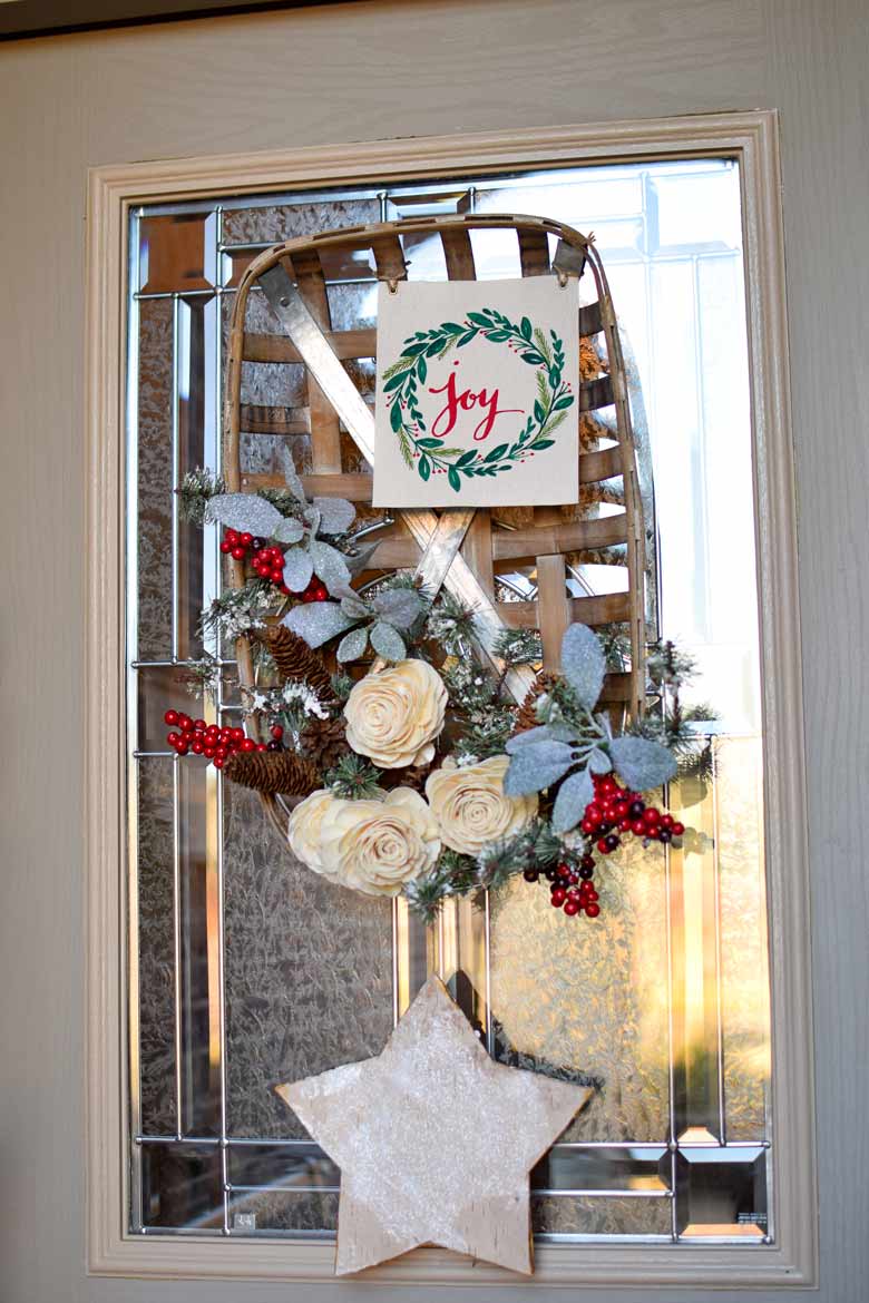 A winter wreath made from white roses, evergreens, berries and more on a tobacco basket hanging on a door.