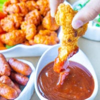 crispy chicken strip being dipped in homemade sweet and spicy bbq sauce