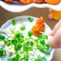 buffalo chicken bites being dipped in a homemade blue cheese dip