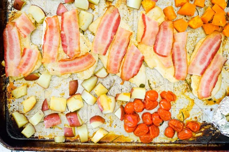 partially baked bacon is placed on top of almost done chicken to finish cooking in the oven.