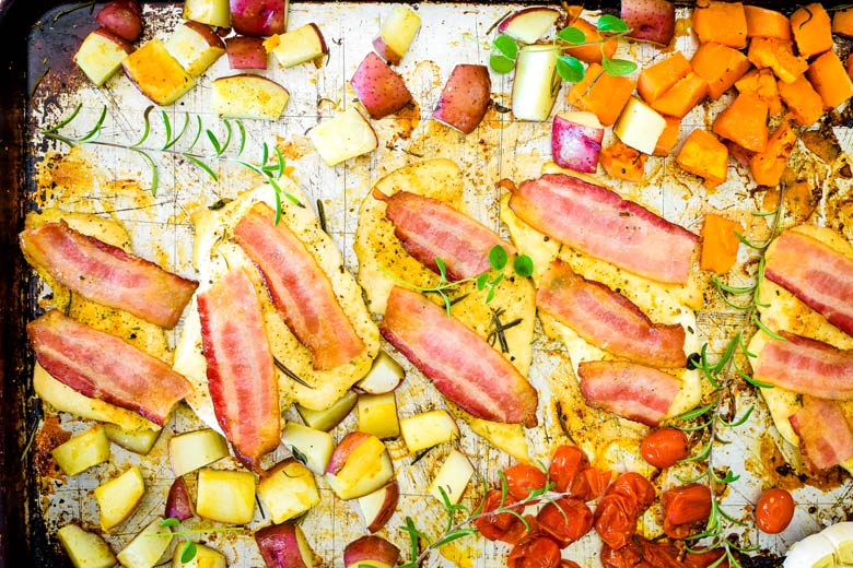 sheet pan full of veggies and chicken with bacon slices