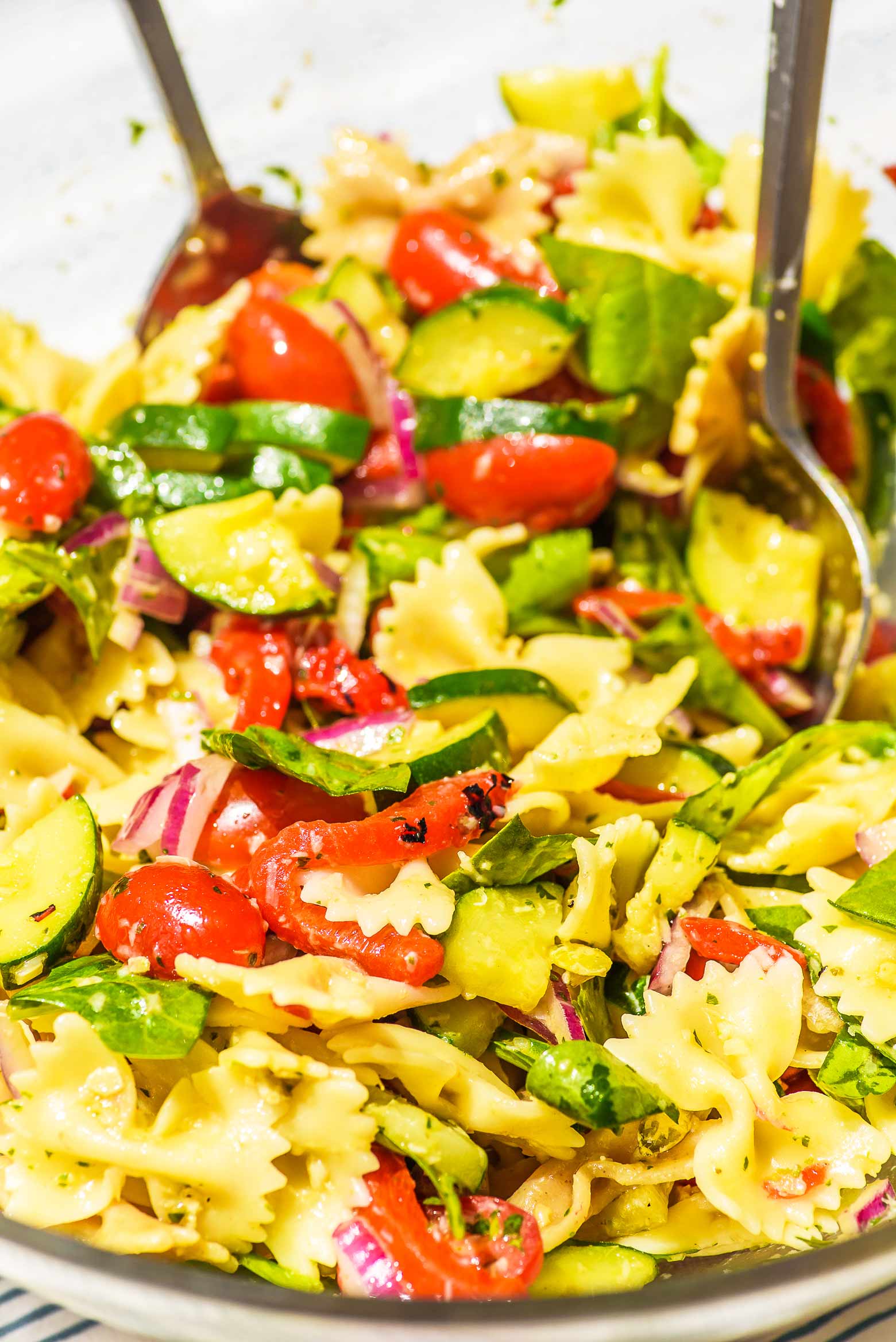 tossing up a bowl of pasta salad with red peppers and artichokes