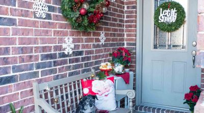 Christmas decor on front porch with a dog on a bench