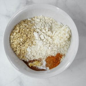 Dry ingredients in a white bowl including coconut and oatmeal
