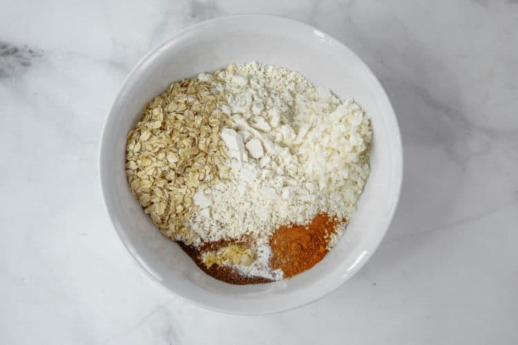 Dry ingredients in a white bowl including coconut and oatmeal