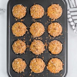 muffins in a grey tin out of the oven next to a towel