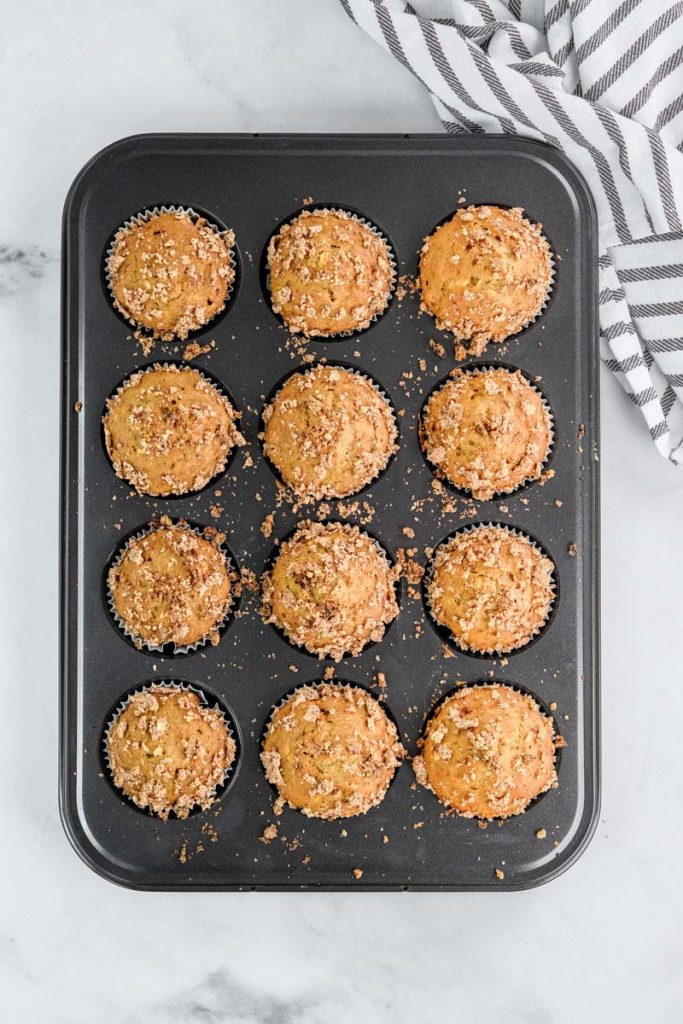 muffins in a grey tin out of the oven next to a towel