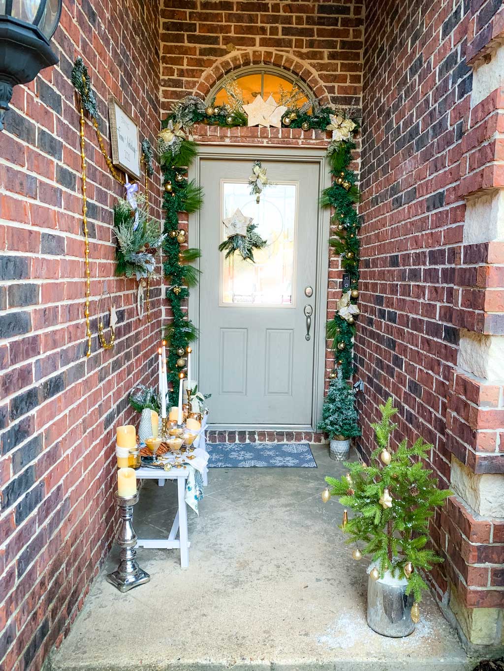 A bench on front porch with a wall of wreaths and a garland covered from door. 