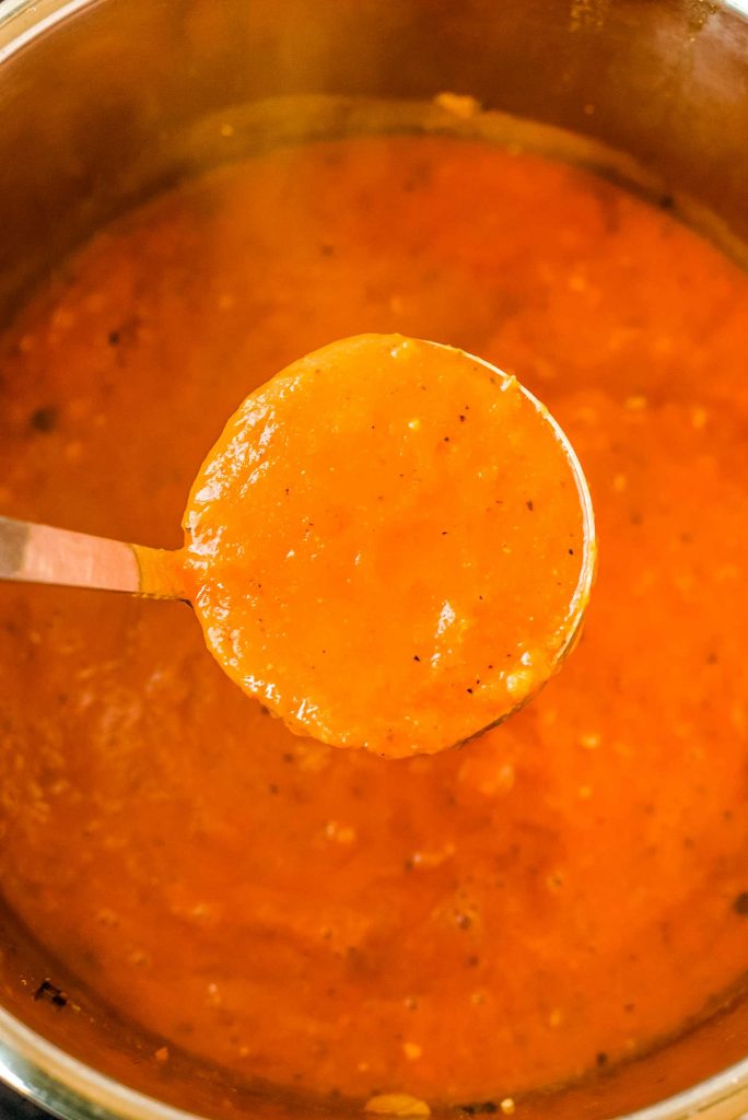 a scoop of roasted red pepper soup made in a pressure cooker pot