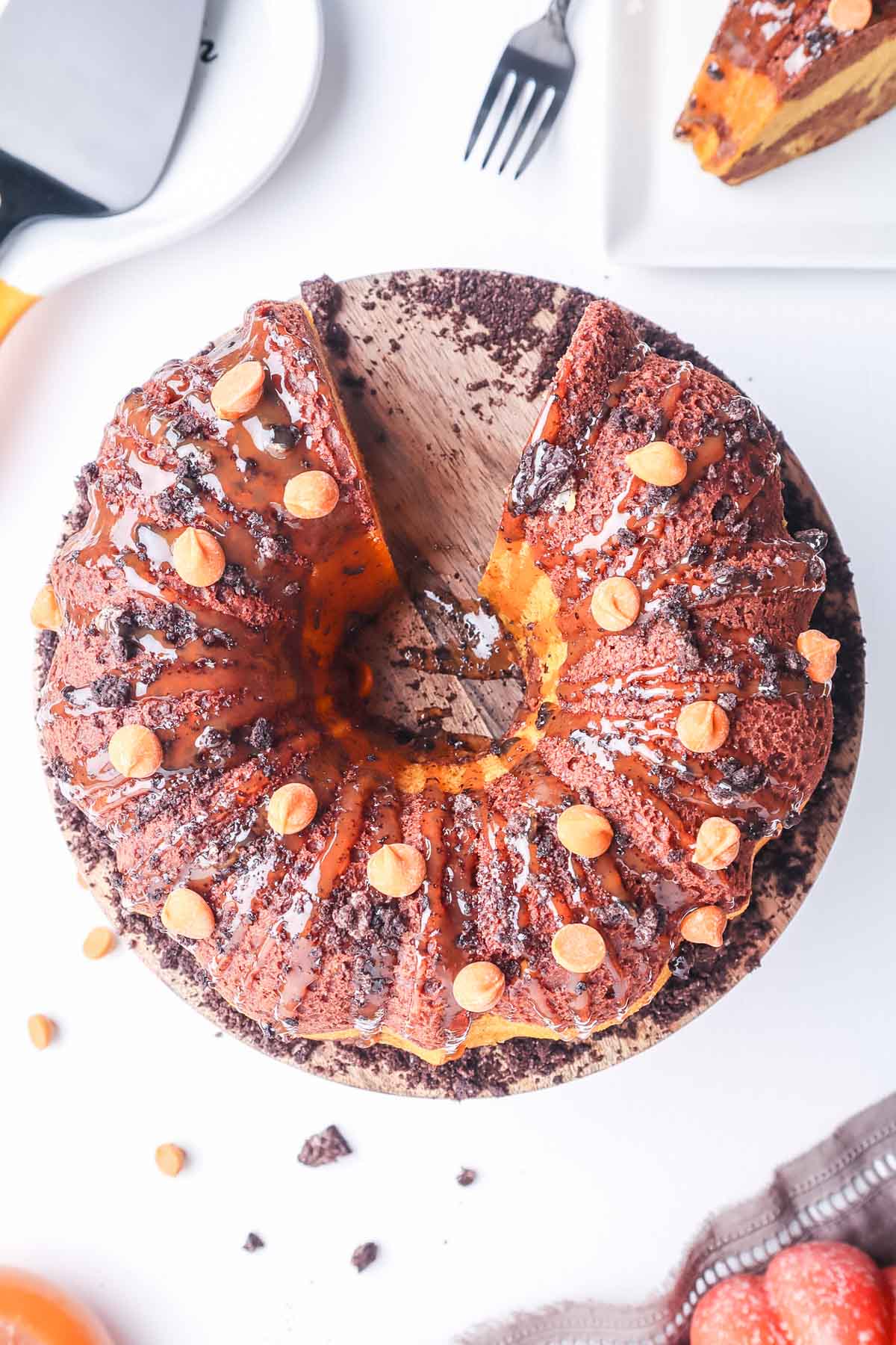 an orange and brown round bundt cake on a wooden cake stand missing one piece. 