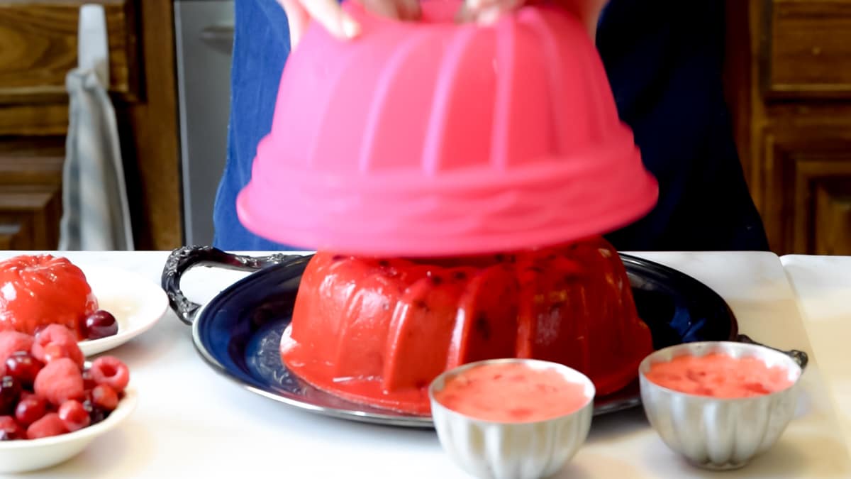 A jello ring on a platter with the pan it was set in on top as it is being released.
