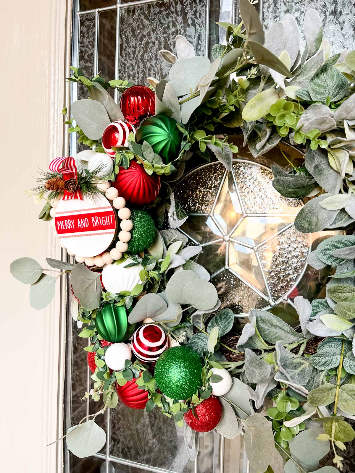 A basic 22 inch lamb's ear wreath from Walmart that has added decorations of red, green and white Christmas ornaments of varying size. 