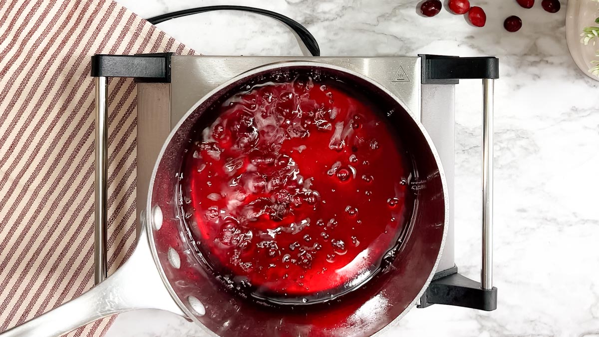 A red liquid boiling bubbles in a saucepan.