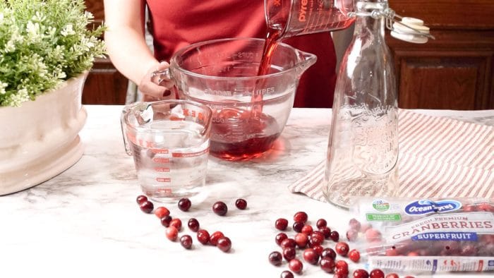 Pouring cranberry syrup into a large glass bowl.