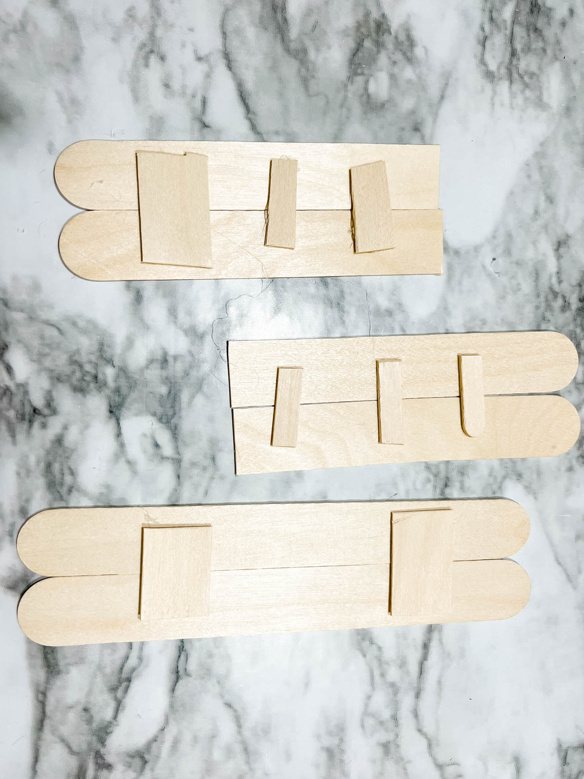 Large wooden craft sticks glued together side by side by using smaller pieces of craft sticks on top to secure.