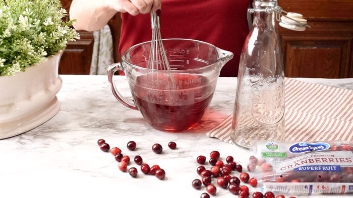 Whisking cooled cranberry syrup with vodka.