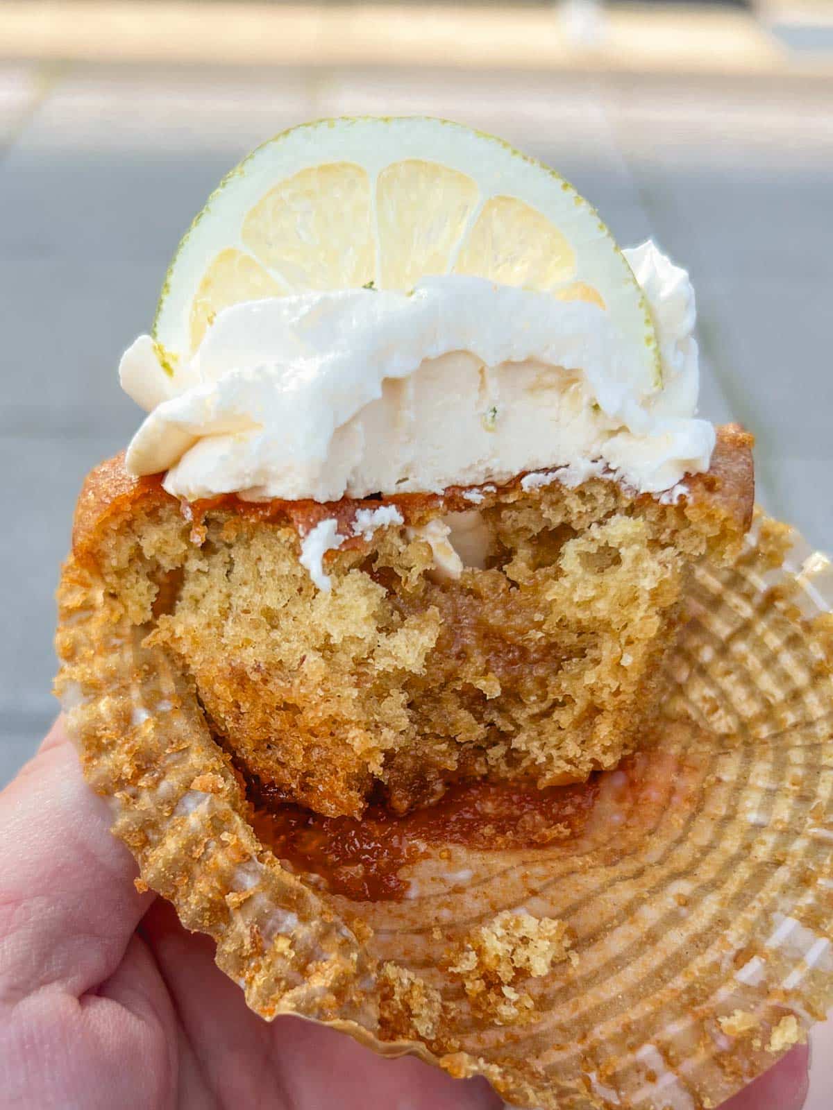 a lemon lime citrus cupcake with a bite taken out of the middle and a lemon wedge topping it