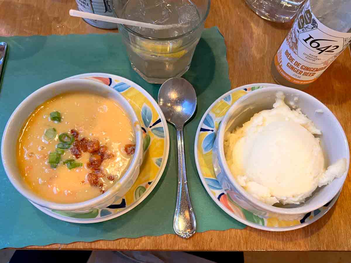 a bowl of split pen soup topped with green onions next to a bowl of plain mashed potatoes.
