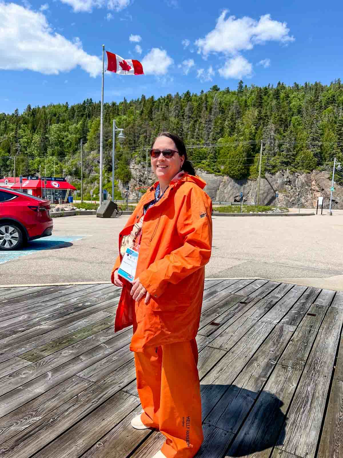 a female posing in front of a Canadian flag in an orange Fishermans outfit